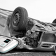 A flipped over and destroyed car with some Amico consoles and controllers near it.